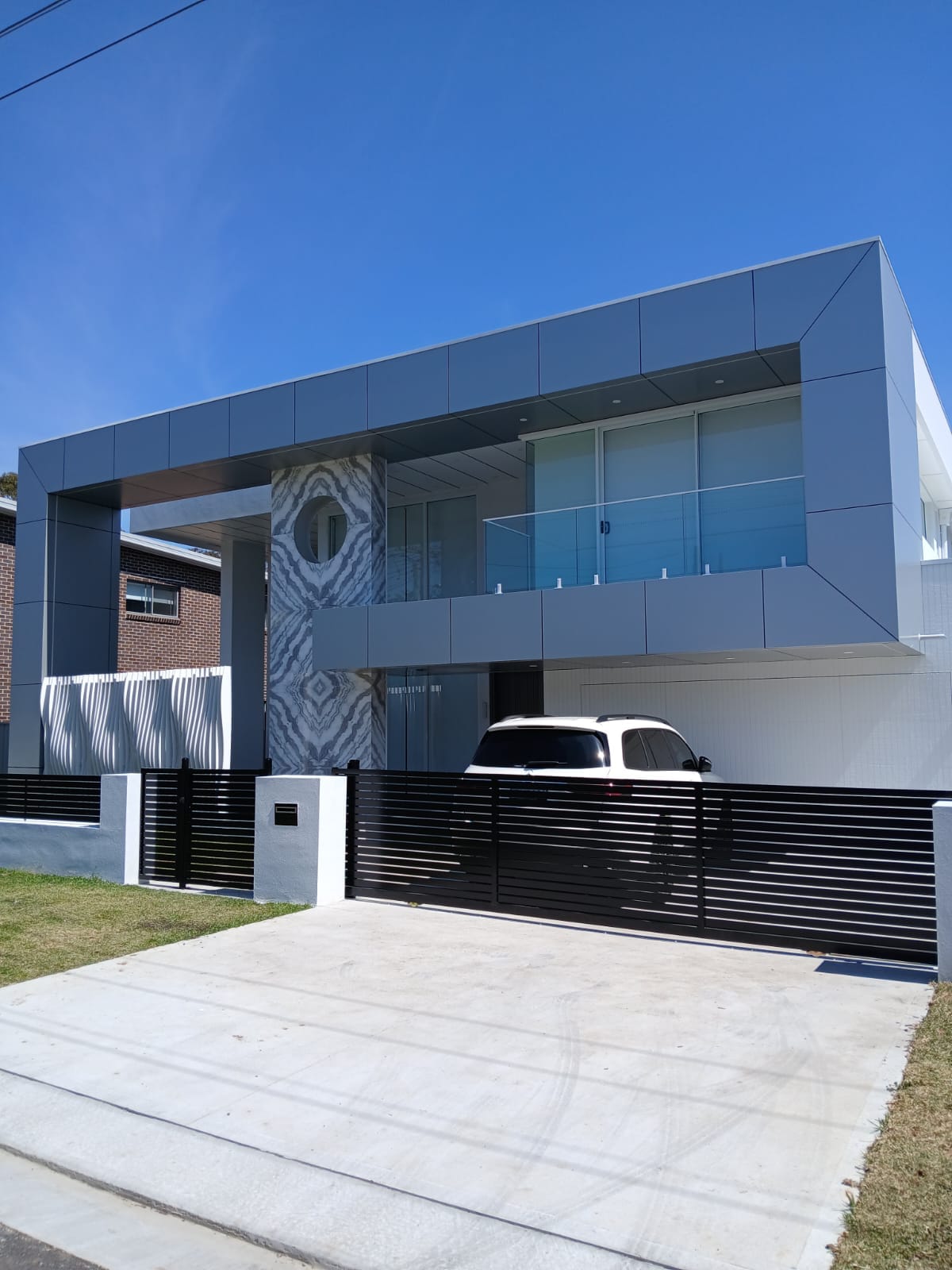 Black horizontal slat automatic driveway gate at a modern residential property.