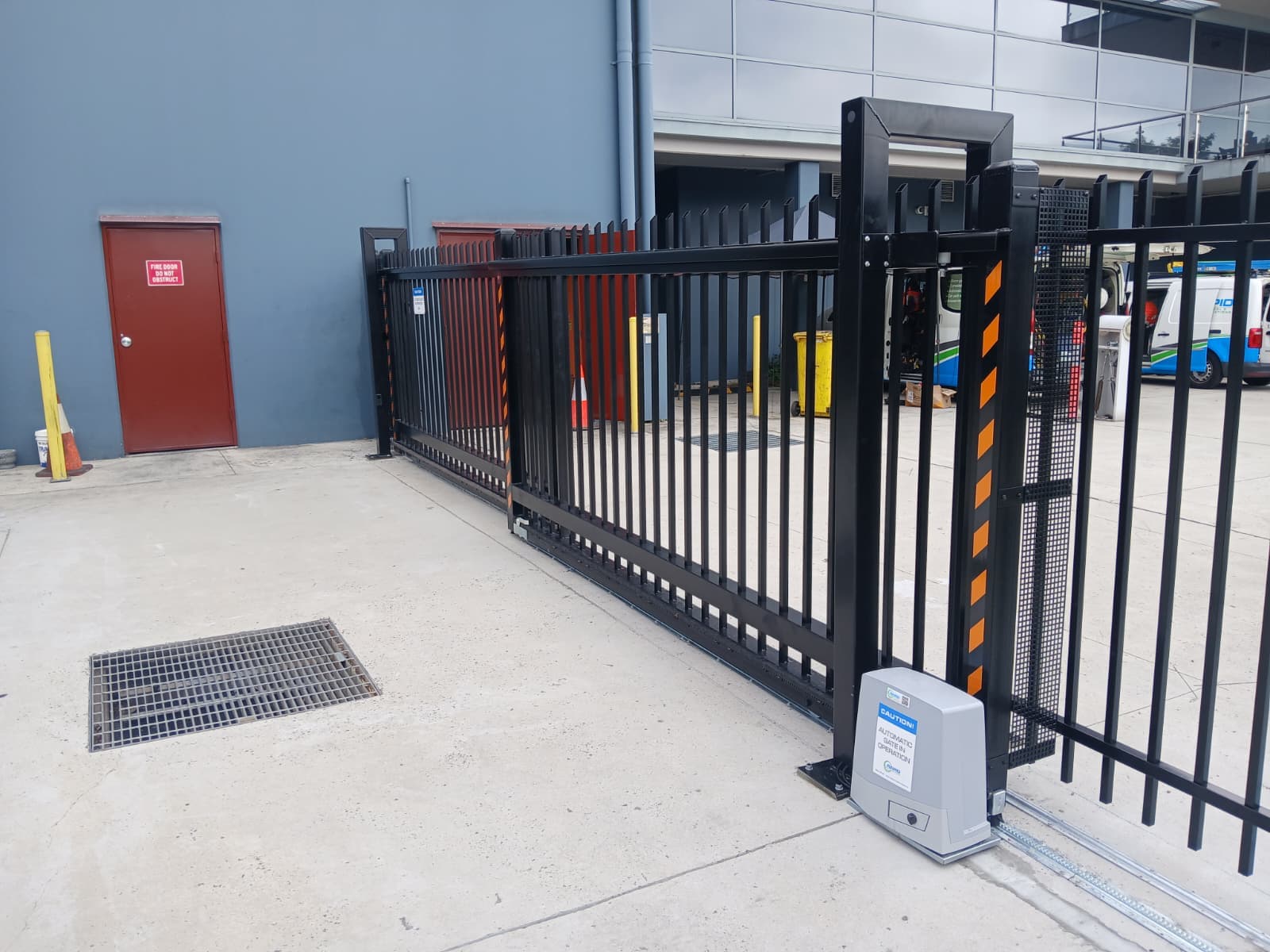 Automatic sliding gate and grey gate motor at a commercial facility entrance.