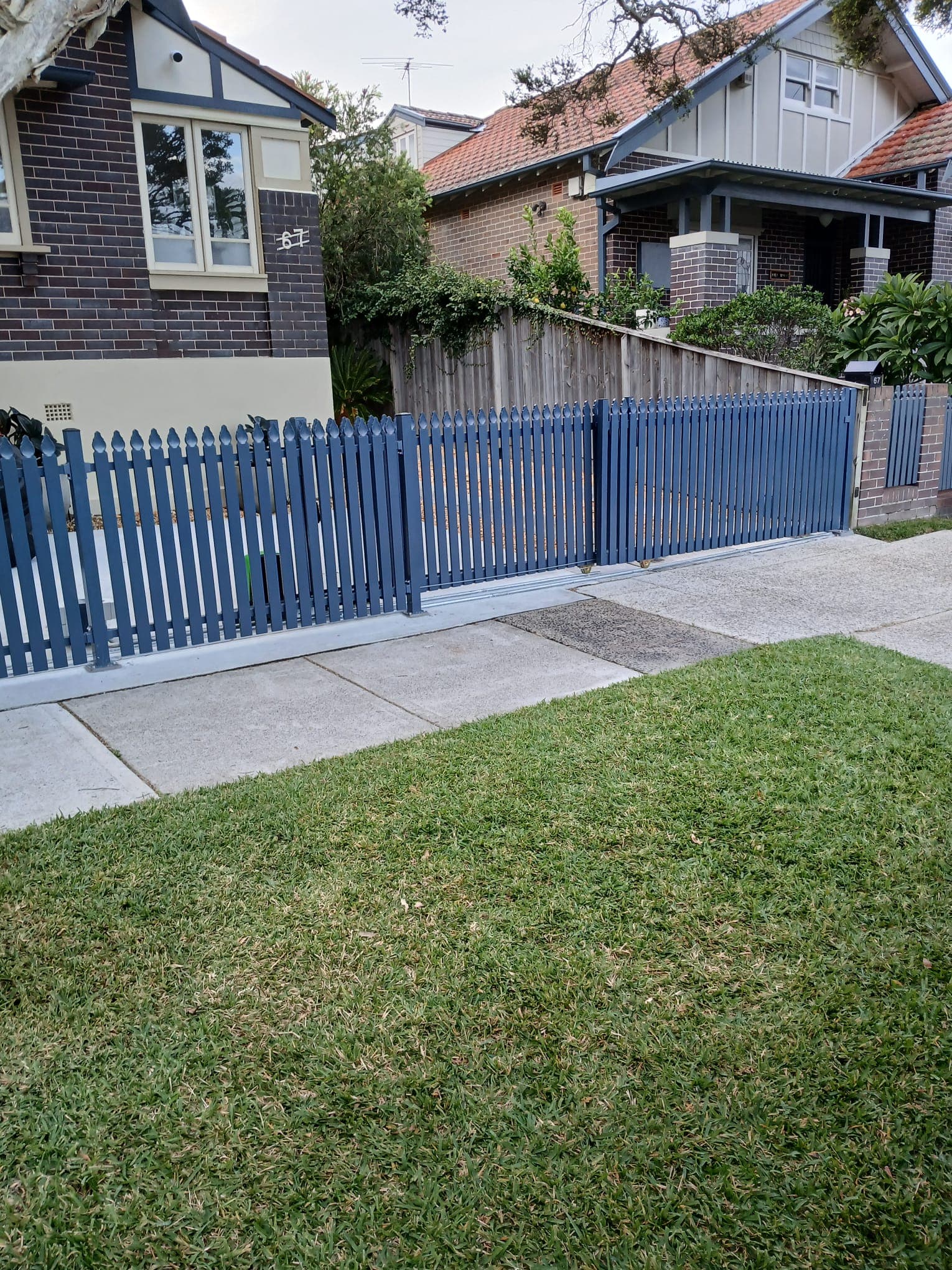 Blue picket sliding gate integrated with a residential streetscape