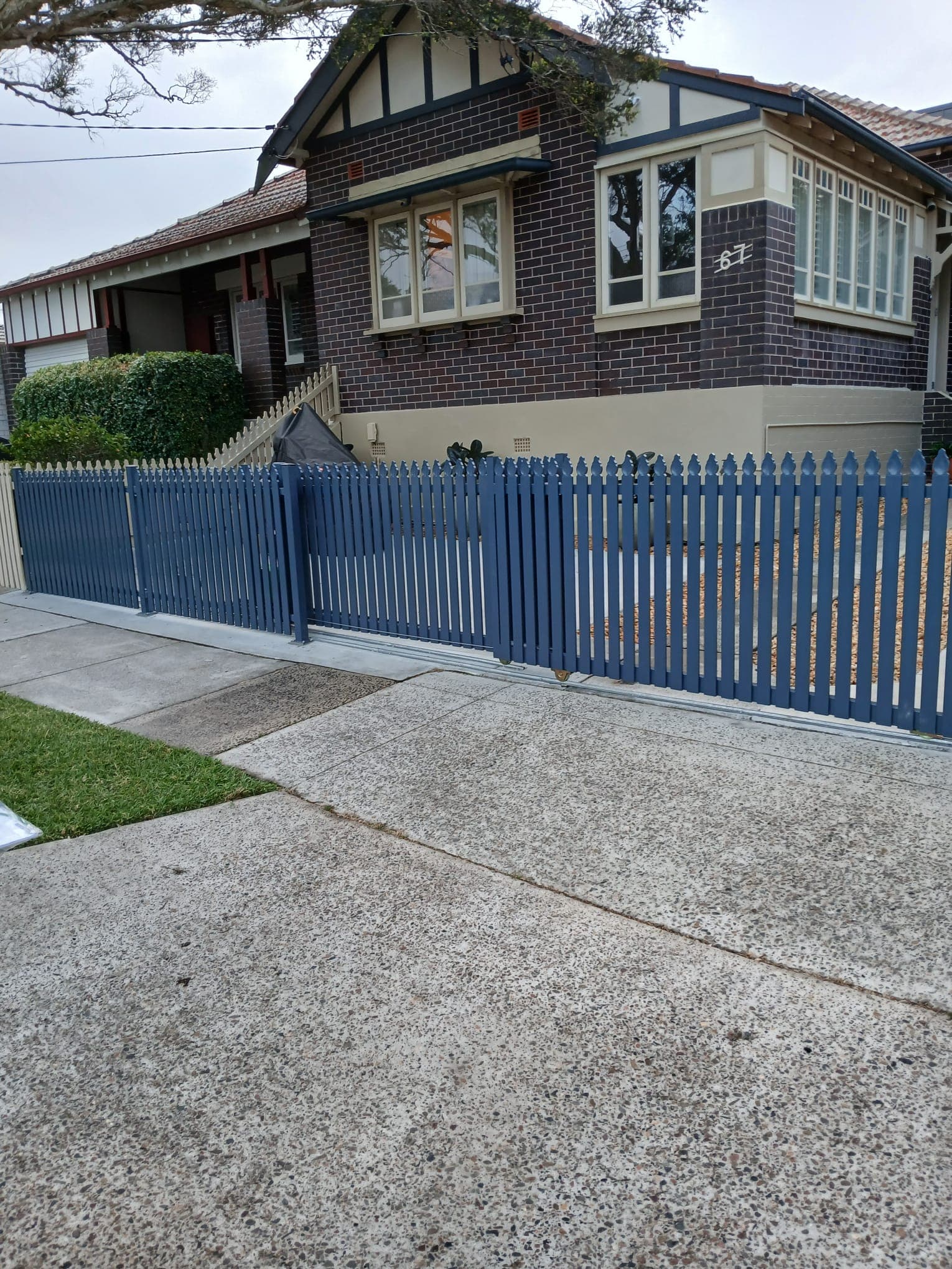 Blue sliding gate spanning a sloping residential driveway