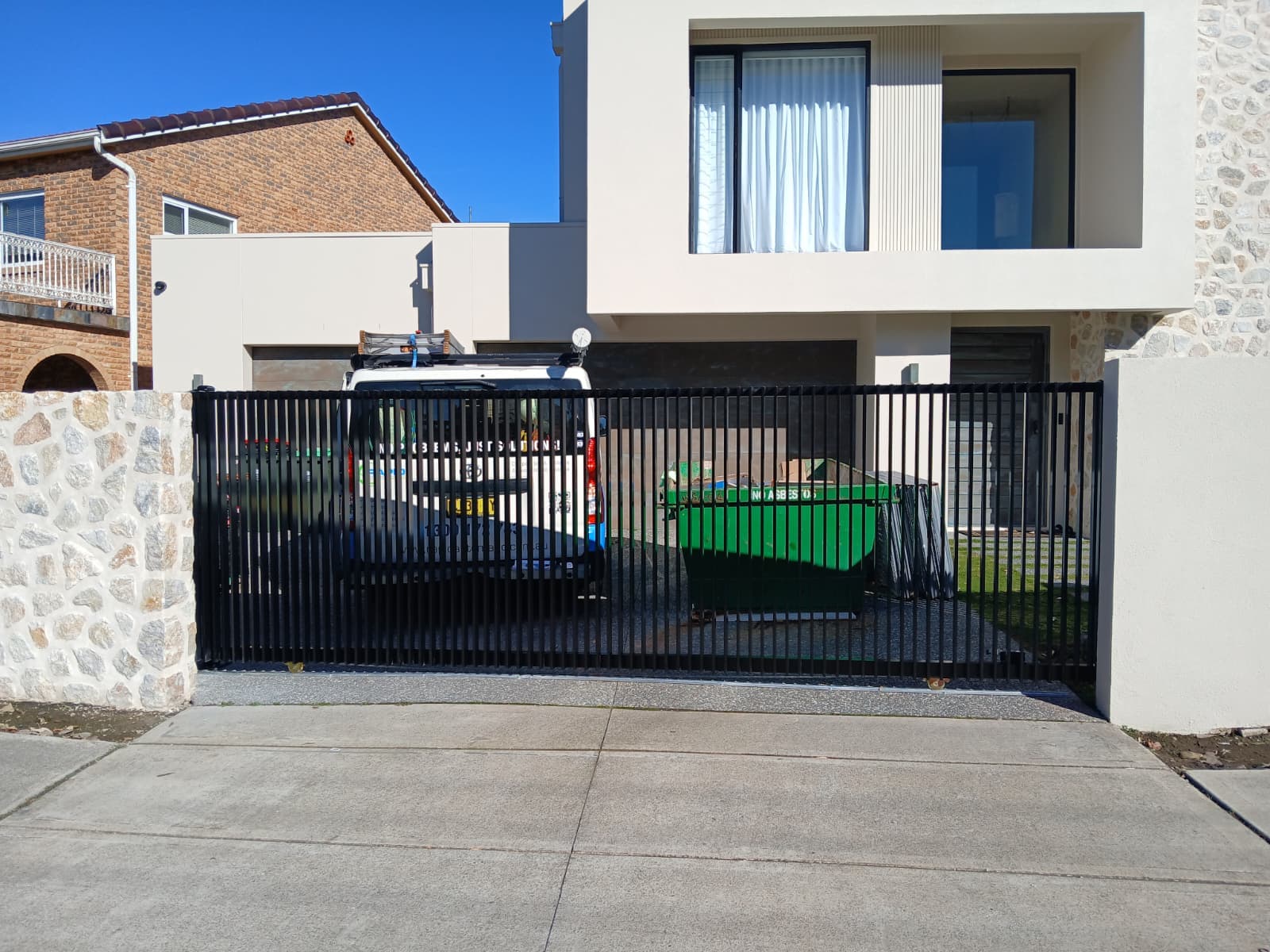 Closed black sliding gate across a modern residential driveway