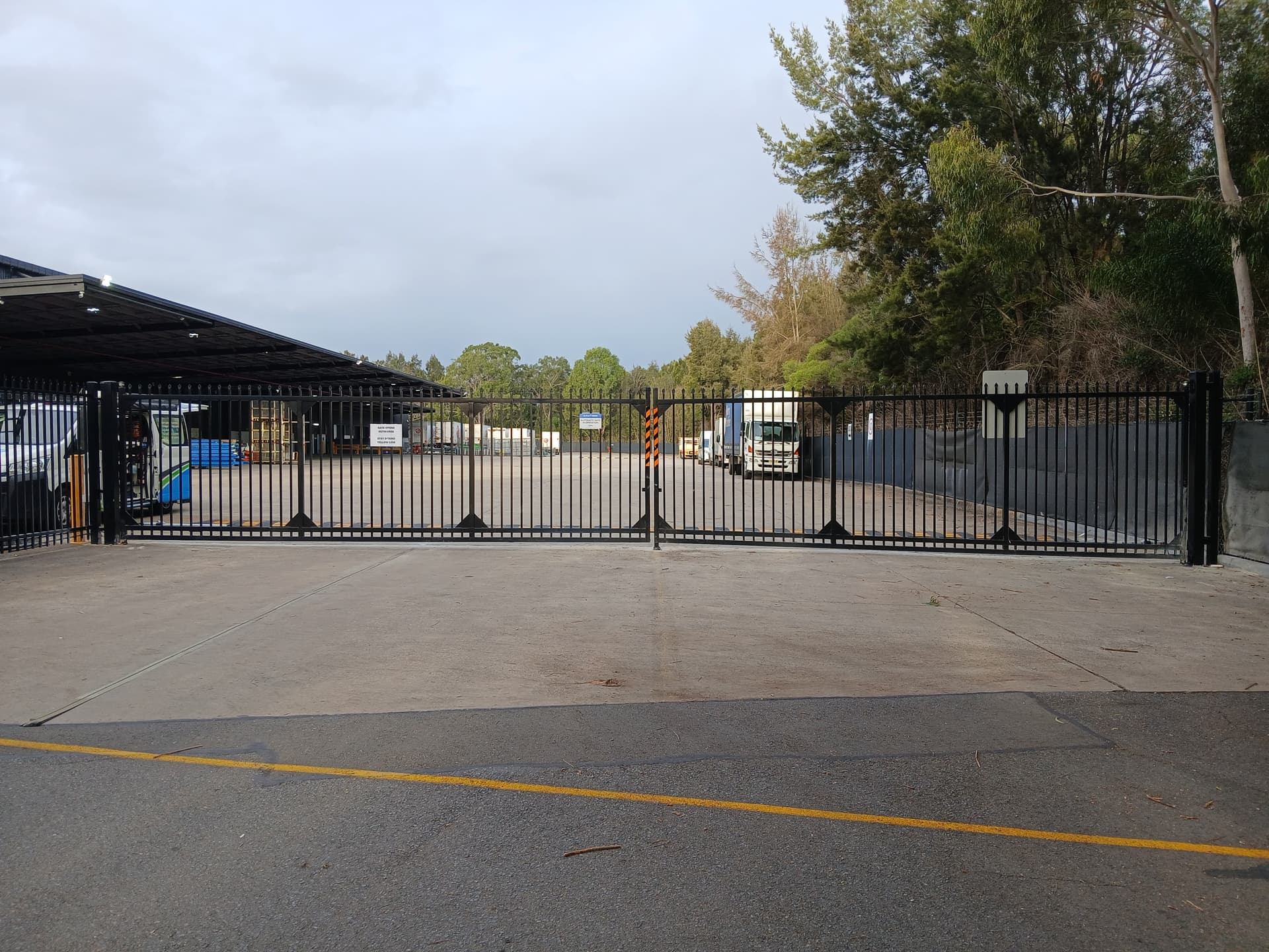 Black commercial swing gates across a facility driveway.