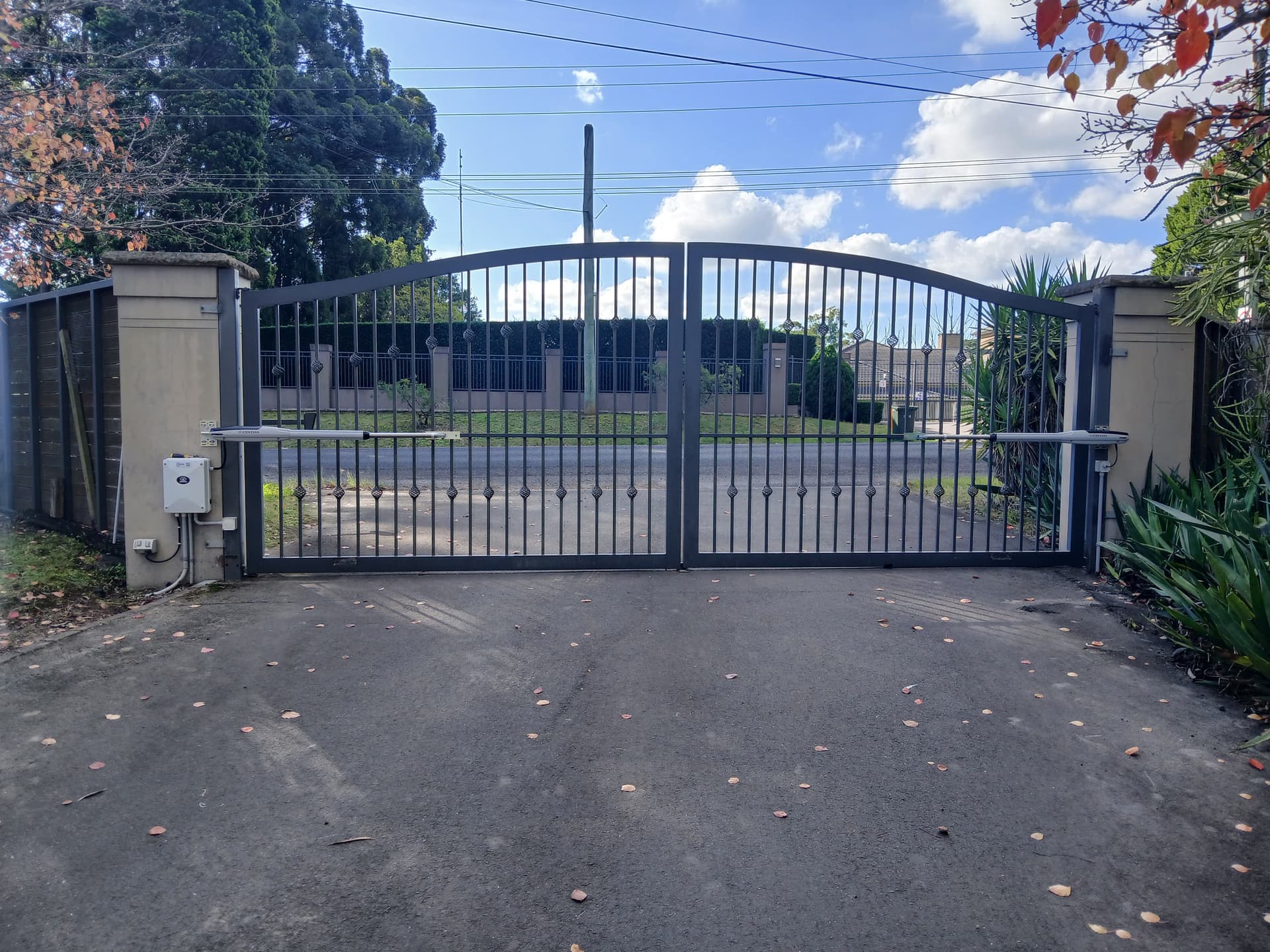 Blue-grey ornamental arched vehicle access gates.