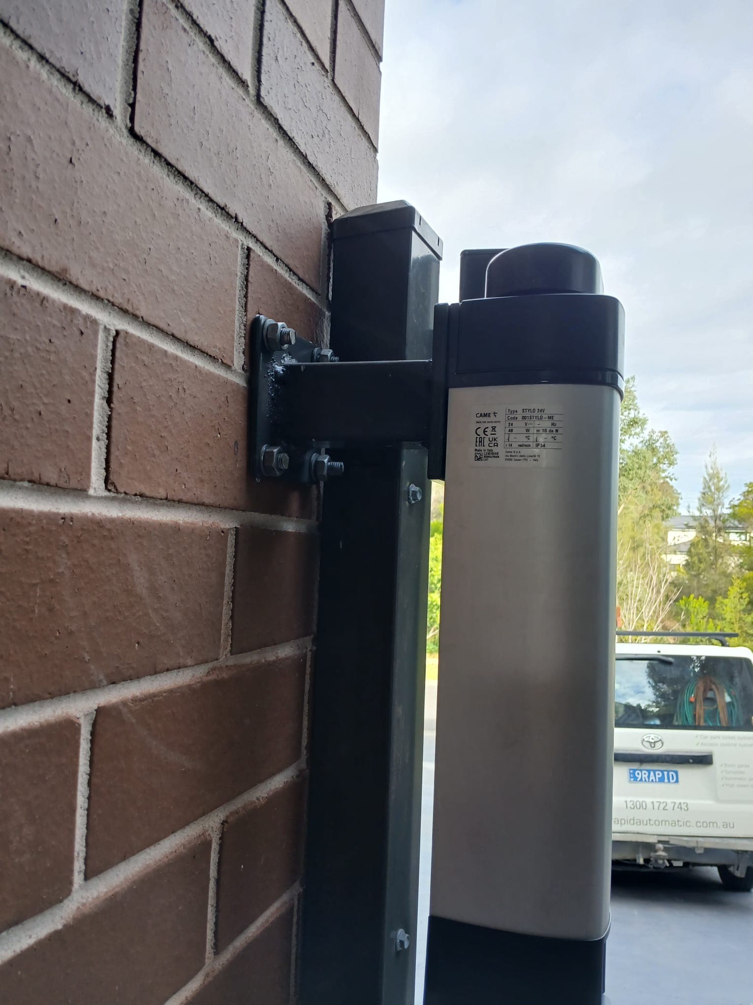 Swing gate opener actuator mounted beside a gate post.