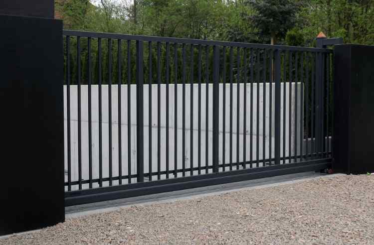 Black automatic gates at the entry to an industrial complex.