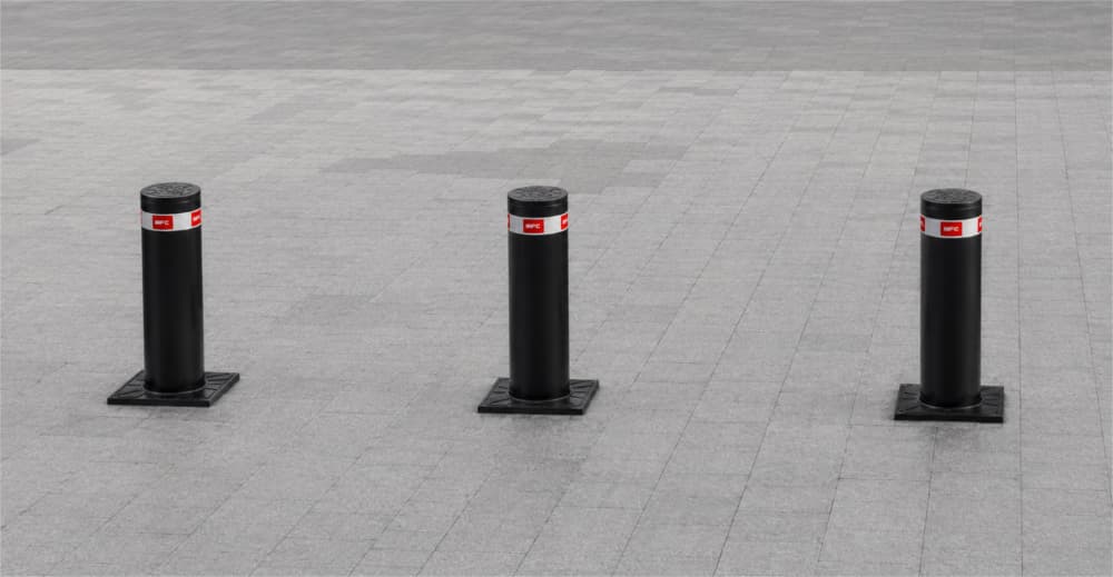 Black high-security bollards installed across a paved commercial access area.